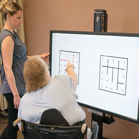 Woman touching the BITS screen while a therapists watches