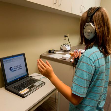 Person with headphones on with raised hands looking at a computer