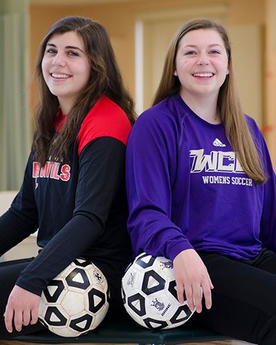 Gabby & Olivia smiling back to back with their soccer balls